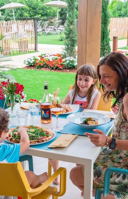 Familie beim Mittagessen im Freien in einem blühenden Garten.