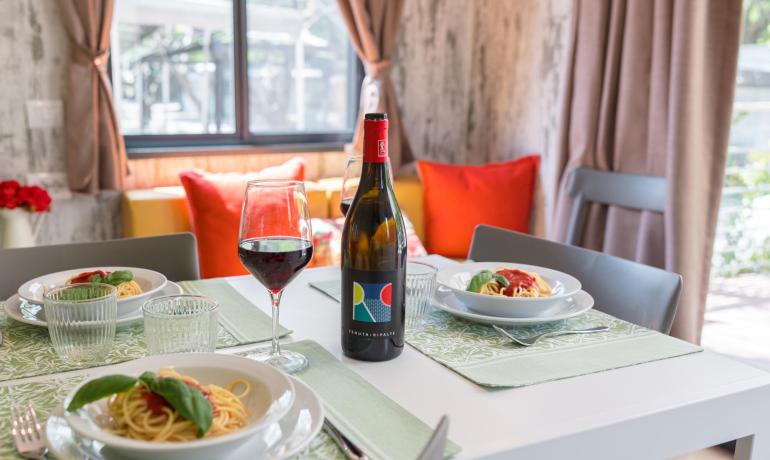 Gedeckter Tisch mit Pasta, Rotwein und Gläsern in gemütlicher Atmosphäre.