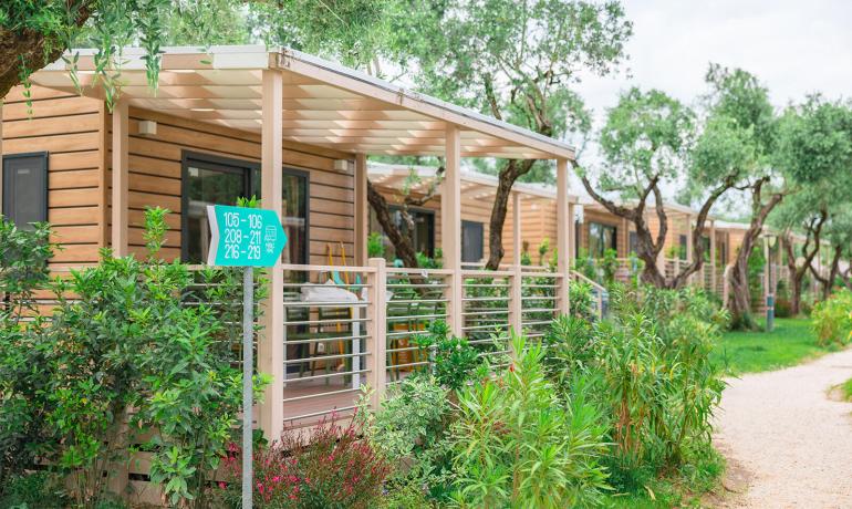 Holzbungalows im Grünen mit Wegen und Beschilderung.