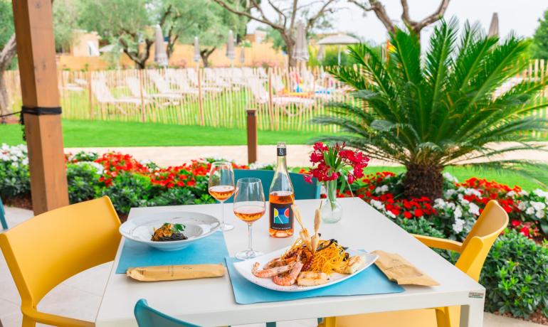 Cena all'aperto con vino e frutti di mare, vista sul giardino.