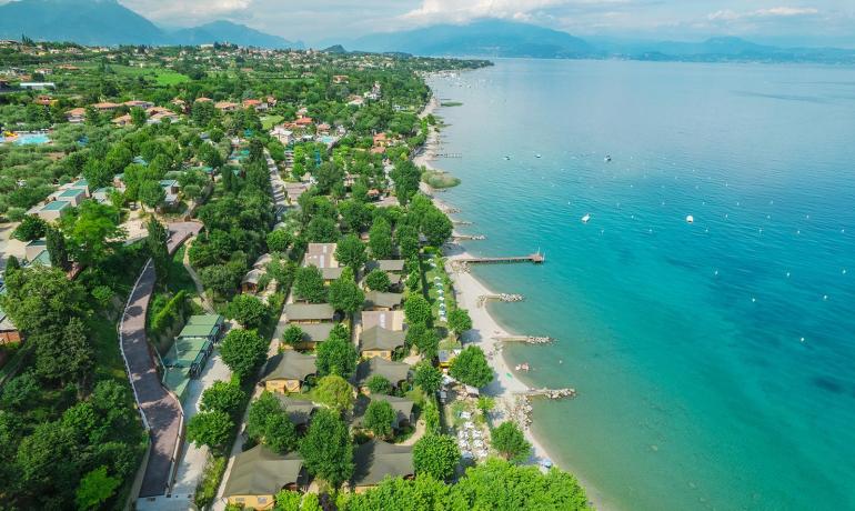 Vista aerea di una costa verde con case e spiaggia.