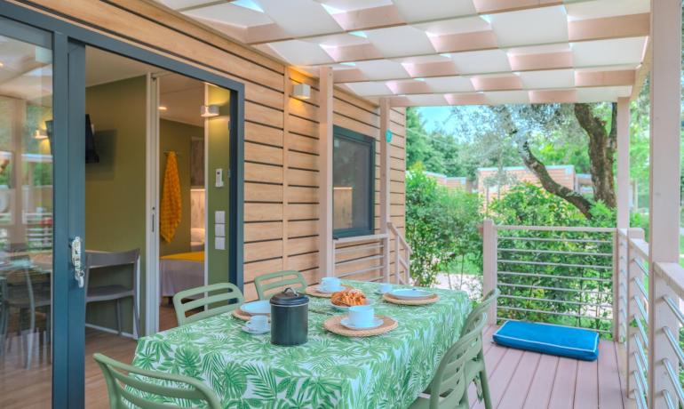 Moderne Veranda mit gedecktem Tisch, umgeben von grüner Natur.