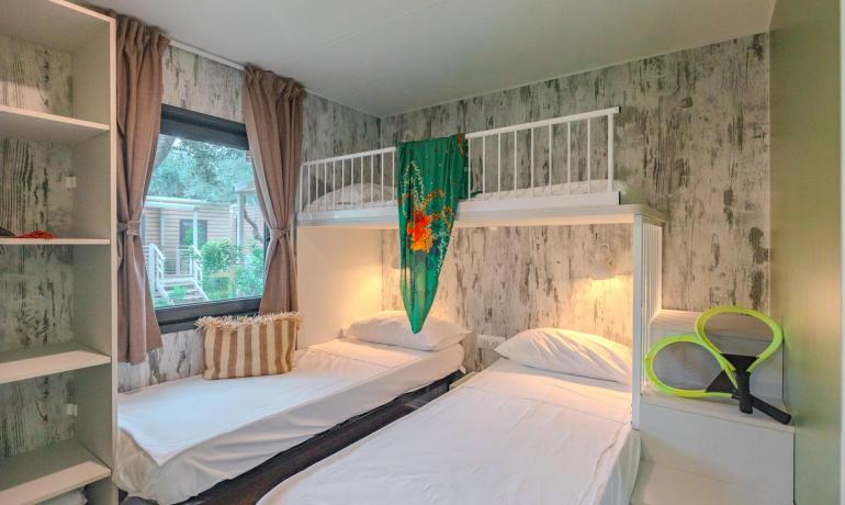 Zimmer mit Einzelbetten, Etagenbett, Fenster und Regalen.