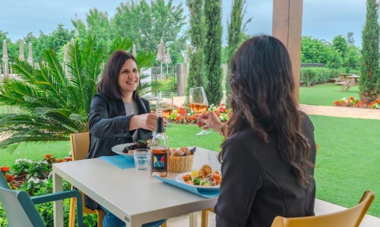 Zwei Personen stoßen im Freien an einem Restaurant an.