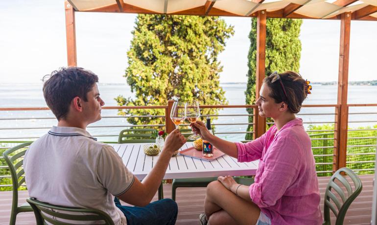 Due persone brindano su una terrazza con vista mare.