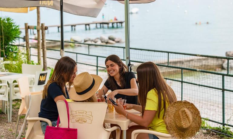 Lächelnde Freunde an der Strandbar, trinken und plaudern.