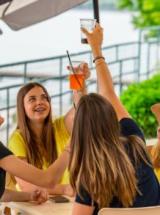 Freunde stoßen draußen zusammen an, lächeln und genießen den Moment.