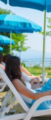 People relaxing under blue umbrellas on a summer day.
