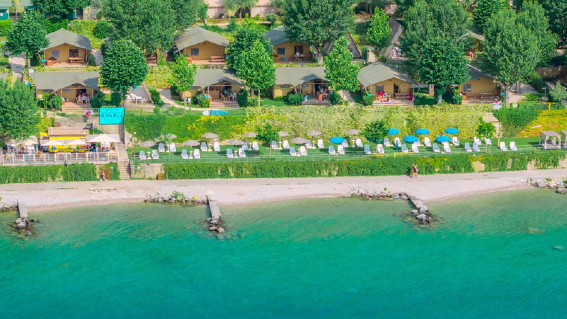 Beach with crystal-clear waters and bungalows surrounded by greenery.
