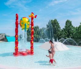 Mutter und Kind spielen in einem Pool mit Wasserspielen.