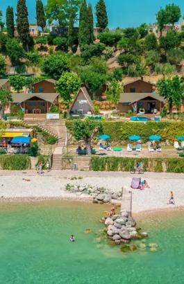 Strand mit Hanghäusern, Sonnenschirmen und grünem Meer.