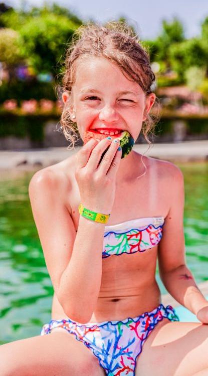 Mädchen im Badeanzug isst Wassermelone in der Sonne.
