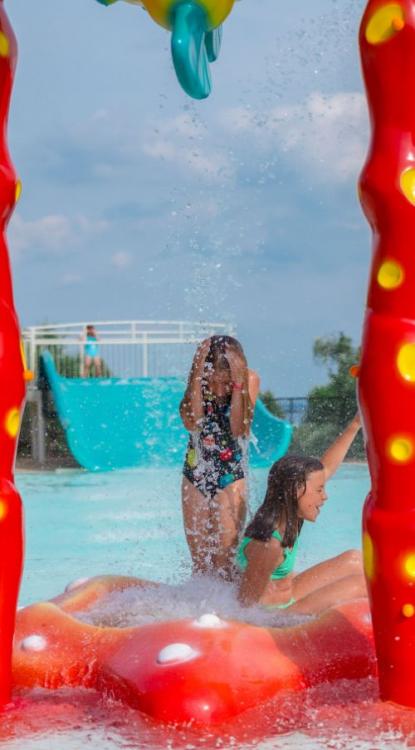 Kinder spielen unter Wassersprays in einem Wasserpark.