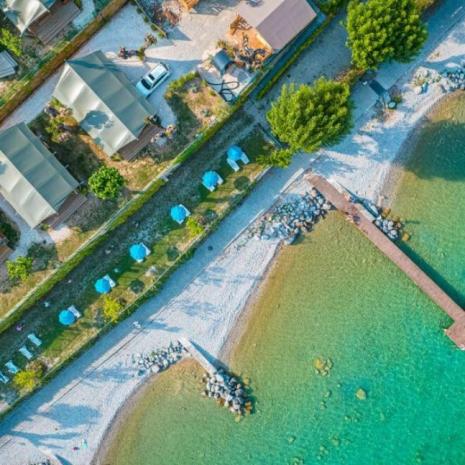 Aerial view of a beach resort with blue umbrellas and clear sea.