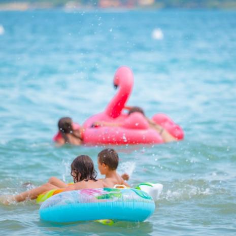 Children play in the sea with colorful inflatables.