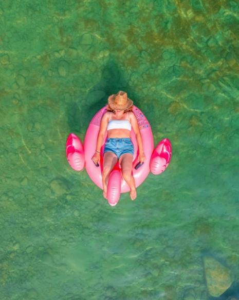 Person on a pink flamingo float in green water.