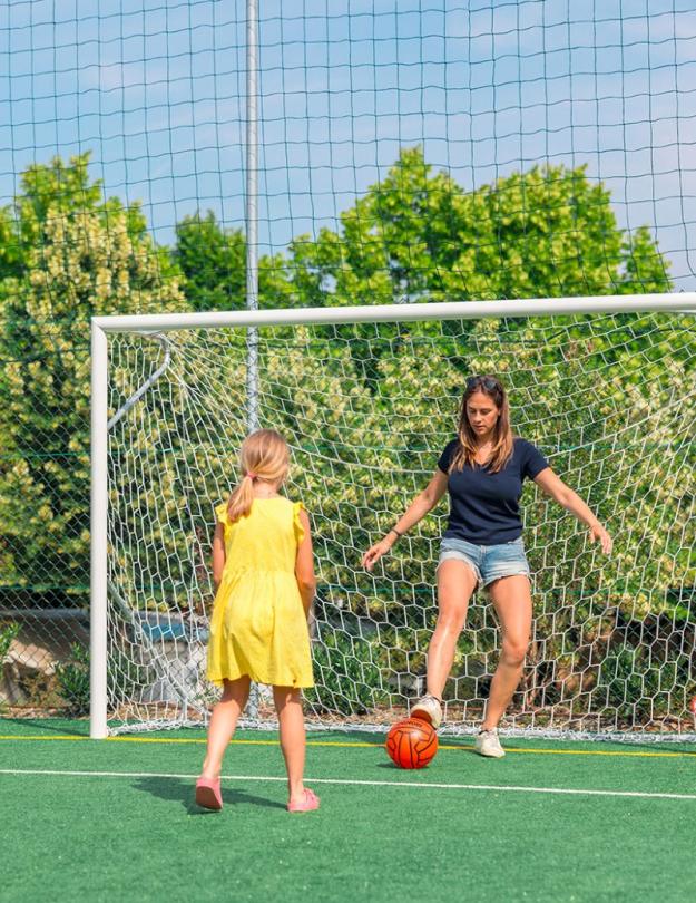 Woman and girl playing soccer on an outdoor field.