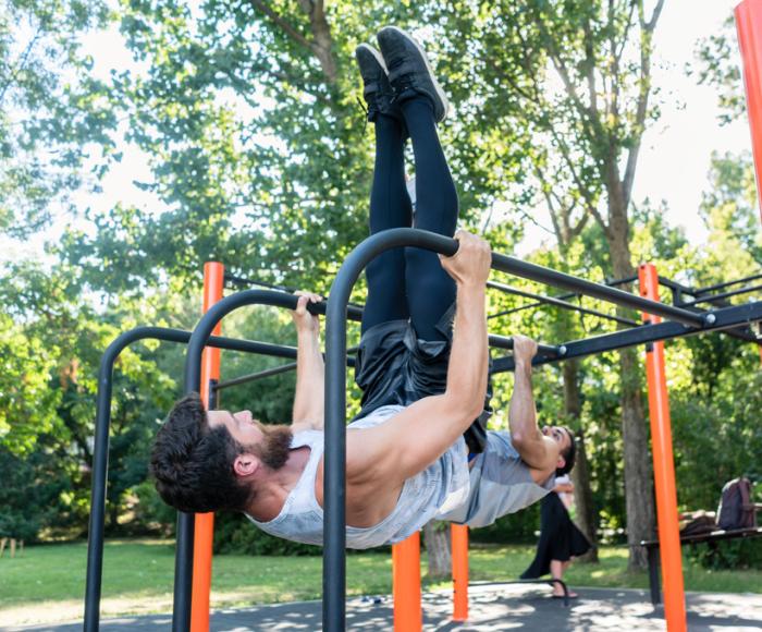 Man exercising on bars outdoors in a park.
