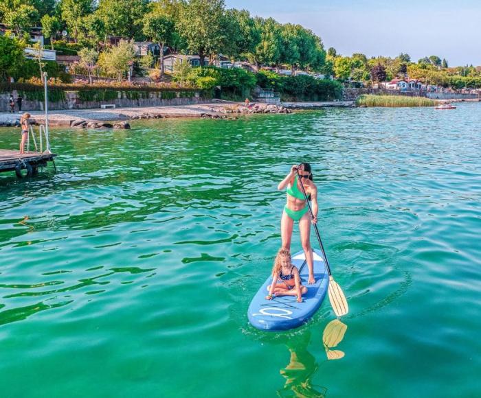 Woman and child on a paddleboard in a green lake.