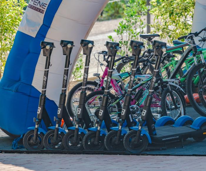 Electric scooters and bicycles parked outdoors.