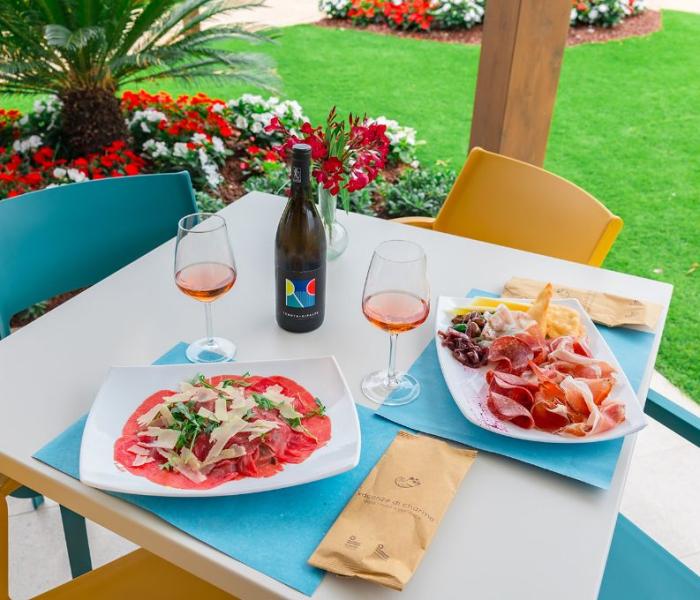 Delicious lunch with rosé wine, carpaccio, and cold cuts in the garden.