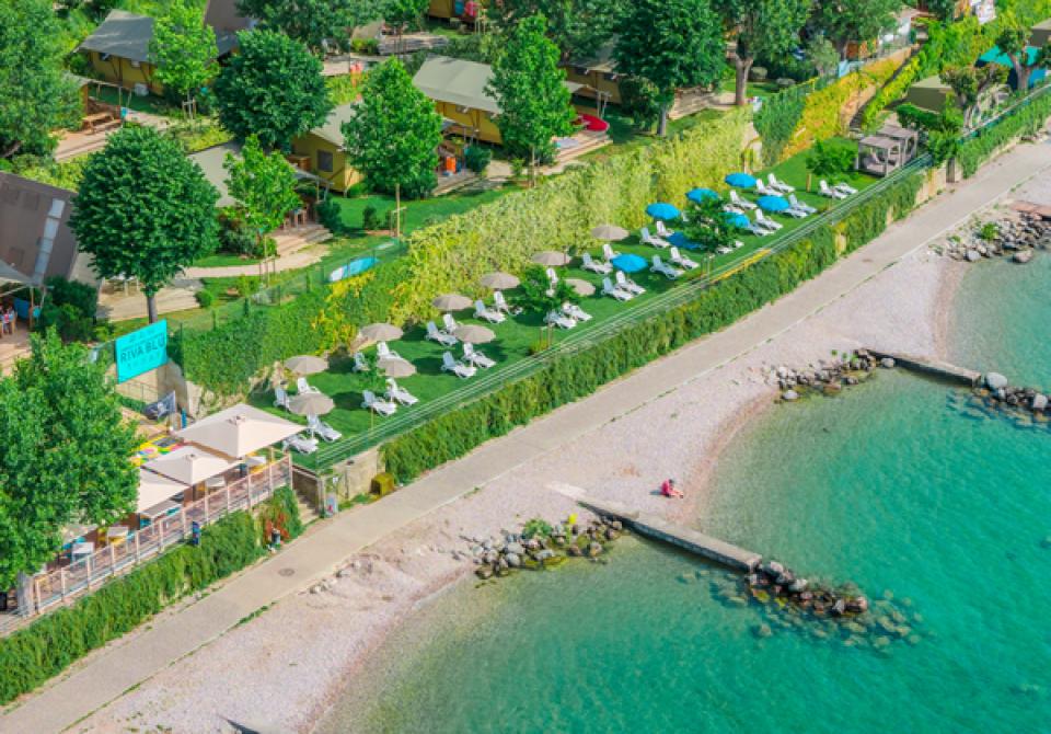 Beach with umbrellas and loungers near a green resort.